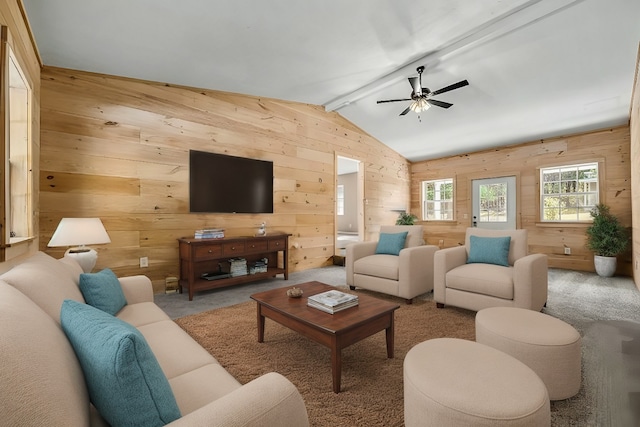 carpeted living room with ceiling fan, wood walls, and lofted ceiling with beams