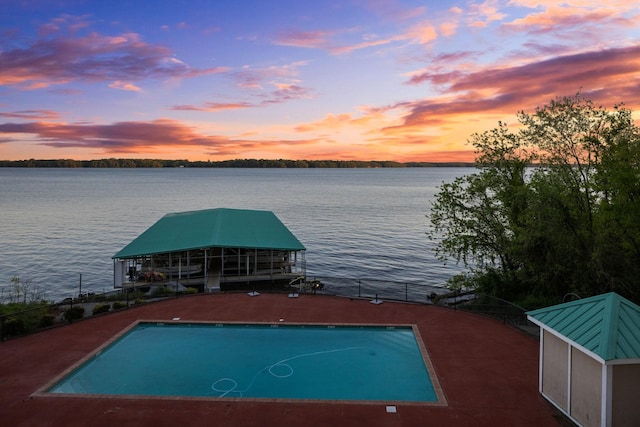 view of pool featuring a water view, a dock, and a fenced in pool
