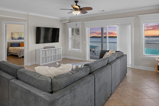 living area featuring baseboards, light tile patterned floors, crown molding, a ceiling fan, and visible vents