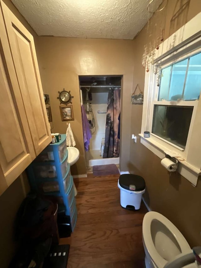 bathroom with toilet, a textured ceiling, shower / tub combo with curtain, and hardwood / wood-style floors