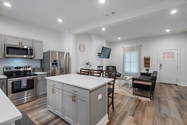 kitchen with gray cabinets, a center island, appliances with stainless steel finishes, and wood-type flooring