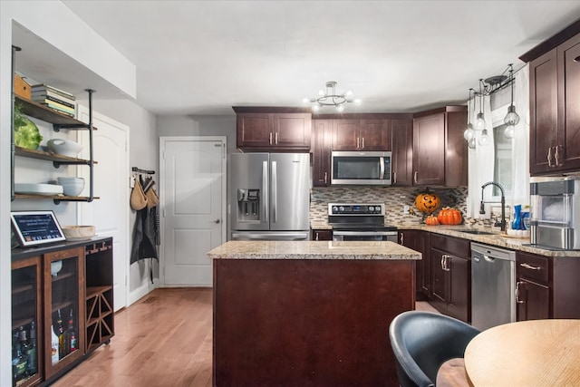 kitchen featuring a kitchen island, light stone countertops, light hardwood / wood-style flooring, sink, and stainless steel appliances