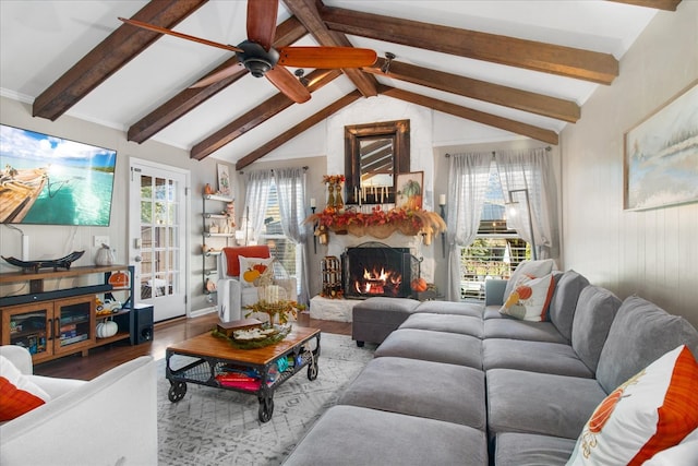 living room featuring hardwood / wood-style floors, lofted ceiling with beams, and a stone fireplace