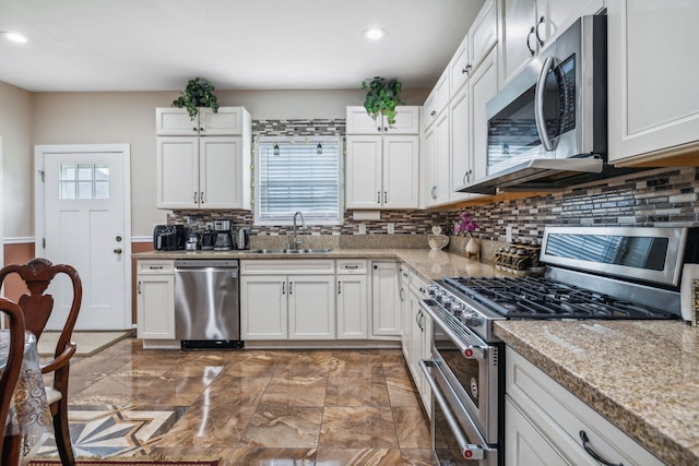 kitchen with light stone countertops, sink, stainless steel appliances, white cabinets, and decorative backsplash