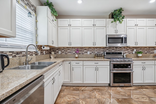 kitchen featuring appliances with stainless steel finishes, white cabinets, tasteful backsplash, and sink