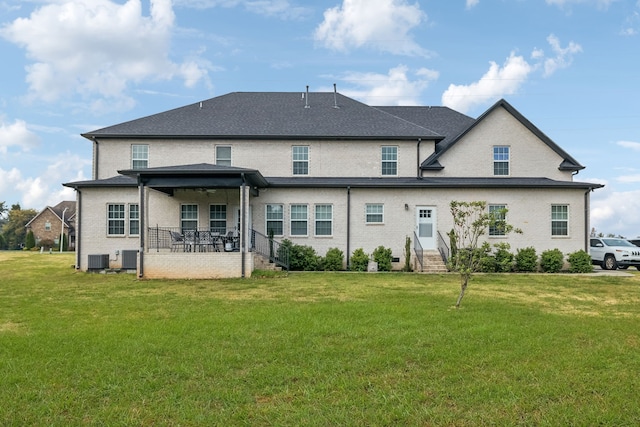 rear view of house featuring central AC unit and a lawn