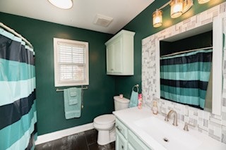 bathroom with vanity, toilet, backsplash, and a shower with shower curtain