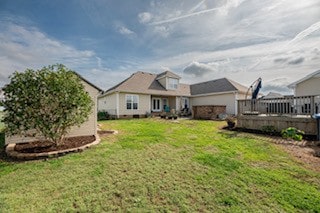 rear view of property featuring a lawn and a wooden deck