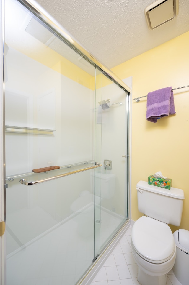 bathroom with tile patterned flooring, toilet, and an enclosed shower