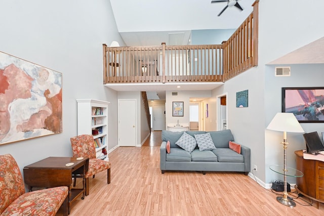 living room with ceiling fan, light hardwood / wood-style floors, and a high ceiling