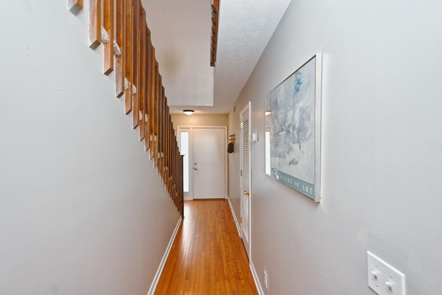 hallway with a textured ceiling and light wood-type flooring