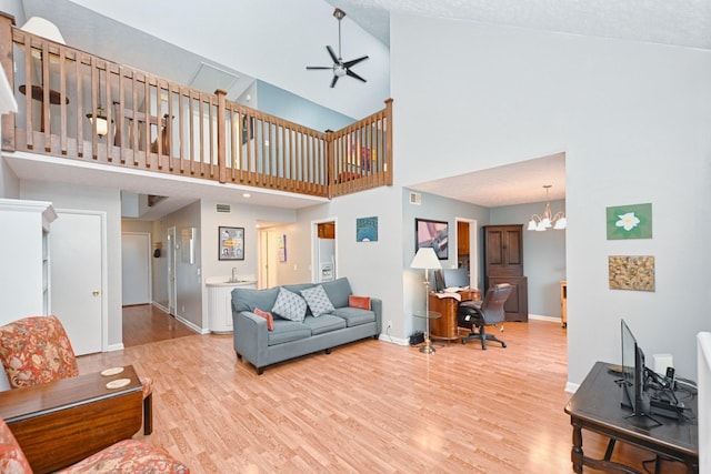 living room featuring a textured ceiling, hardwood / wood-style floors, high vaulted ceiling, and ceiling fan with notable chandelier