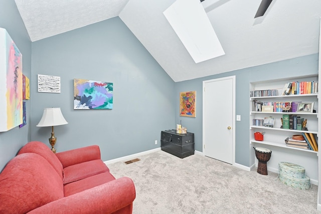 sitting room with a textured ceiling, light colored carpet, and vaulted ceiling with skylight