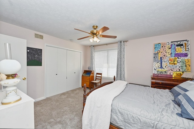 carpeted bedroom with a textured ceiling, a closet, and ceiling fan