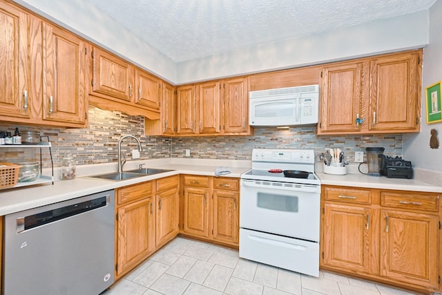 kitchen with sink, tasteful backsplash, a textured ceiling, white appliances, and light tile patterned floors