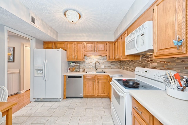 kitchen featuring a textured ceiling, white appliances, backsplash, and sink