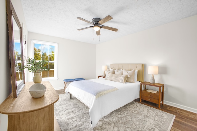 bedroom with a textured ceiling, wood-type flooring, and ceiling fan