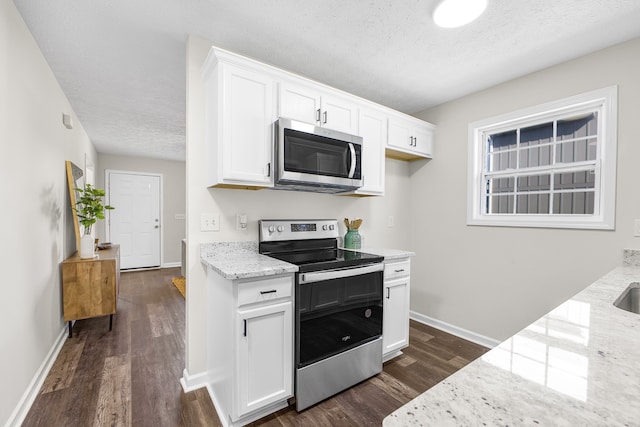 kitchen featuring light stone countertops, appliances with stainless steel finishes, dark hardwood / wood-style floors, and white cabinetry