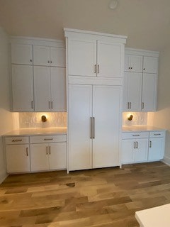 kitchen with decorative backsplash, white cabinets, and light hardwood / wood-style flooring