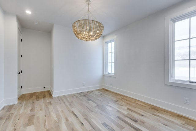 unfurnished room with a chandelier and light wood-type flooring