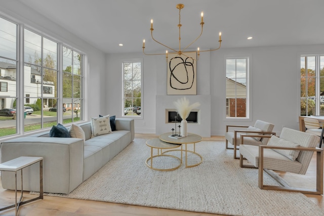 living room featuring an inviting chandelier, a healthy amount of sunlight, and light wood-type flooring