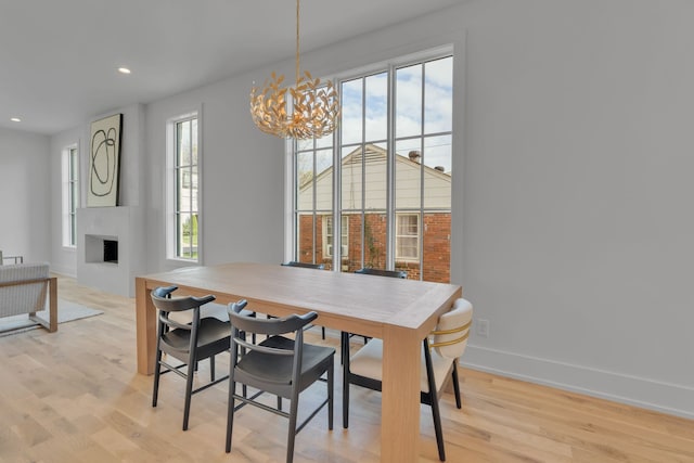 dining space with a notable chandelier, a large fireplace, and light wood-type flooring