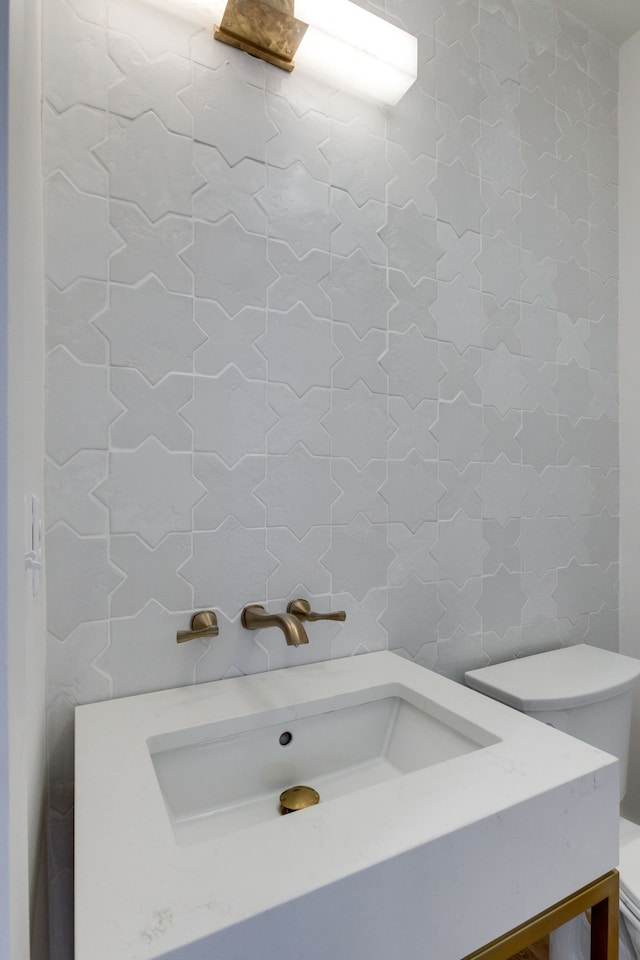 bathroom featuring toilet, tile walls, and sink