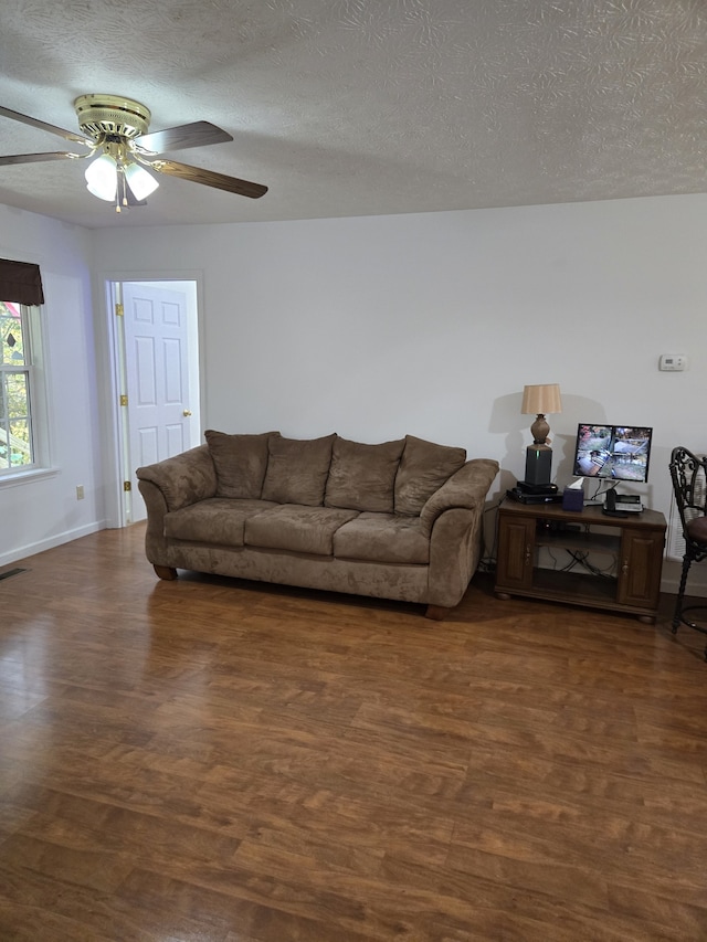 living room with ceiling fan, dark hardwood / wood-style flooring, and a textured ceiling