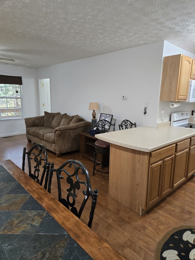 kitchen with kitchen peninsula, dark hardwood / wood-style flooring, white appliances, and a textured ceiling