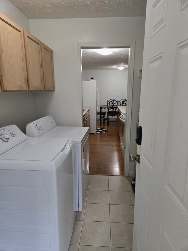 laundry room featuring cabinets, independent washer and dryer, a textured ceiling, and light tile patterned floors