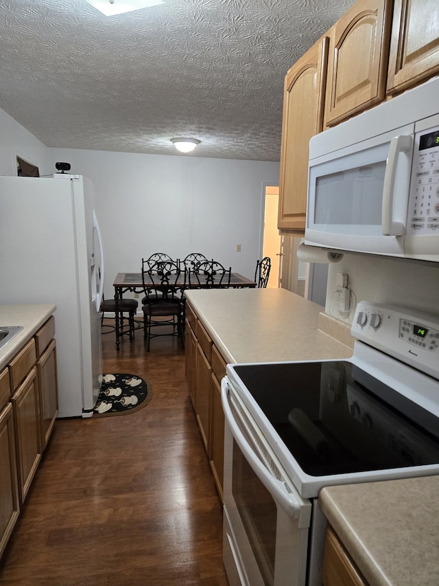 kitchen featuring a textured ceiling, white appliances, and dark hardwood / wood-style floors