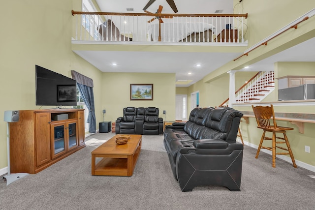 living room with ornate columns, ceiling fan, a towering ceiling, and light colored carpet