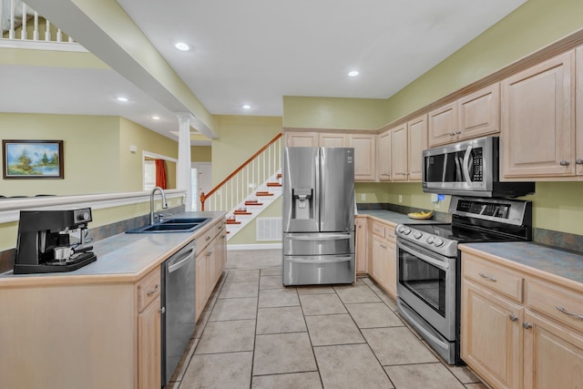 kitchen featuring sink, light brown cabinetry, light tile patterned flooring, stainless steel appliances, and decorative columns