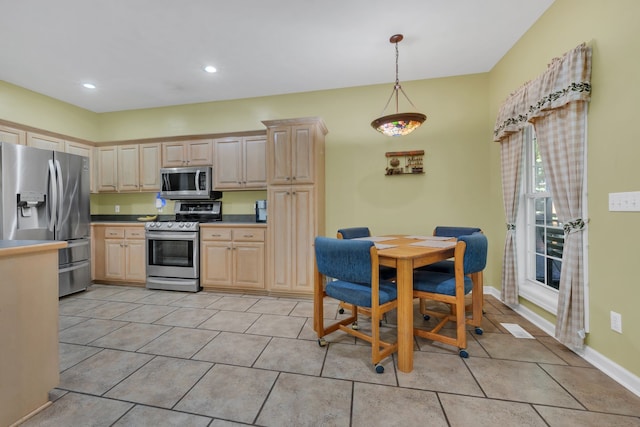 kitchen featuring hanging light fixtures, light brown cabinetry, and stainless steel appliances