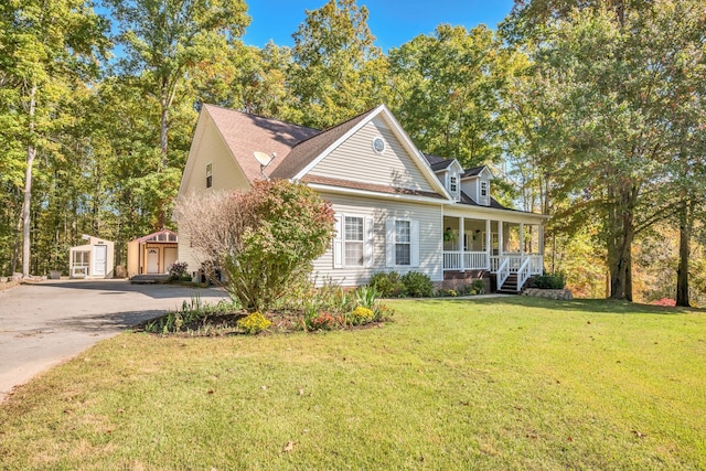 view of front of property featuring a front yard, a storage shed, and covered porch