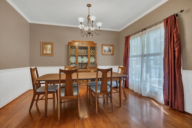 dining area with crown molding, an inviting chandelier, and hardwood / wood-style flooring