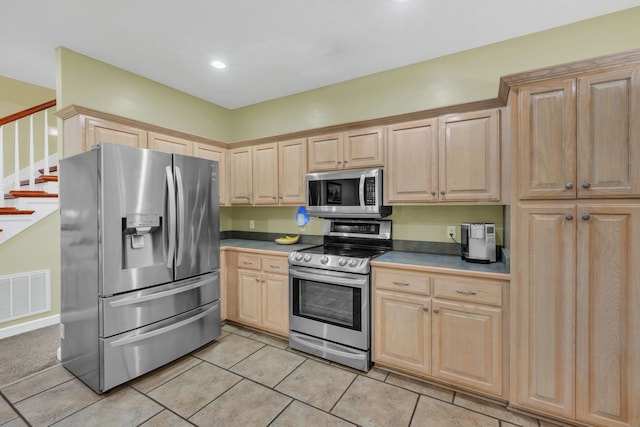 kitchen with light brown cabinetry, light tile patterned flooring, and stainless steel appliances