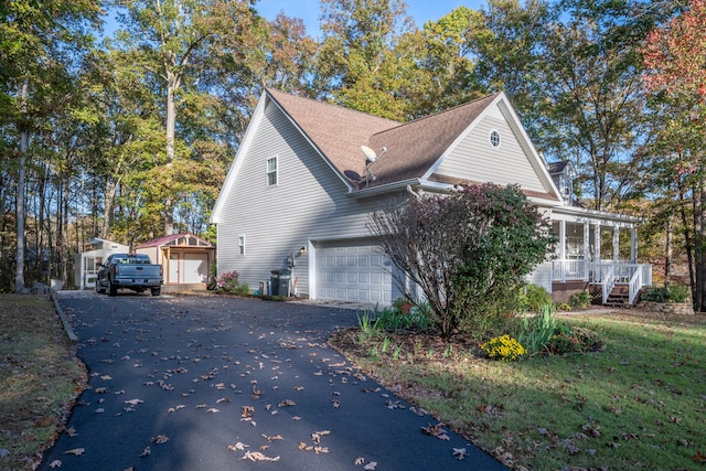 view of property exterior with a garage, covered porch, and an outdoor structure