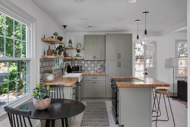 kitchen featuring appliances with stainless steel finishes, gray cabinetry, light tile patterned flooring, and wood counters