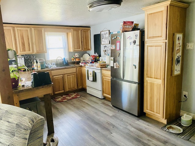 kitchen with sink, a textured ceiling, white electric stove, stainless steel refrigerator, and light hardwood / wood-style flooring