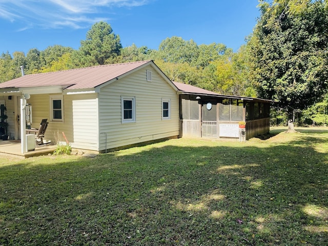 back of property featuring a sunroom and a lawn