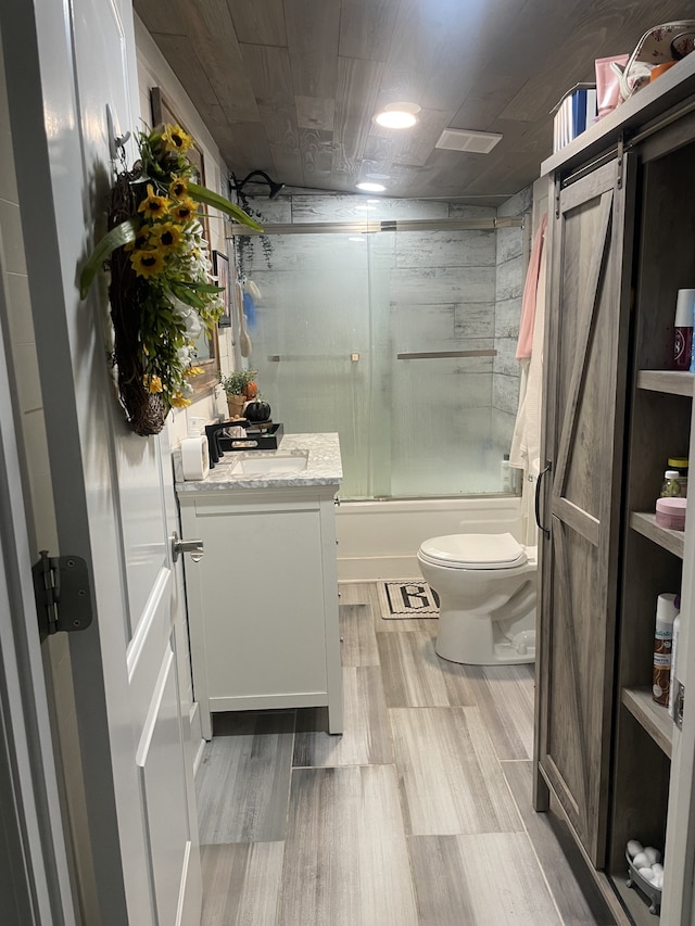 full bathroom featuring vanity, toilet, combined bath / shower with glass door, and hardwood / wood-style floors