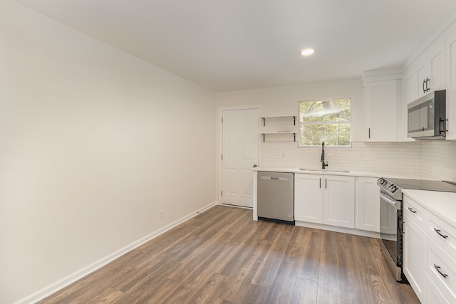 kitchen with appliances with stainless steel finishes, white cabinets, sink, and dark hardwood / wood-style flooring