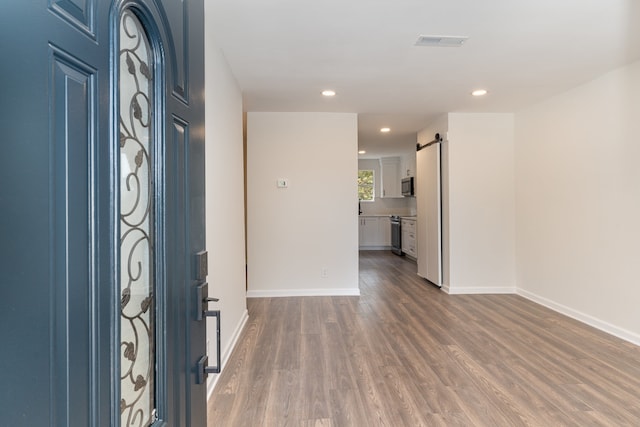 foyer entrance with a barn door and dark hardwood / wood-style floors