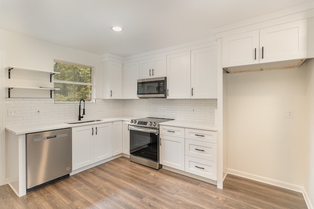 kitchen with sink, backsplash, white cabinetry, stainless steel appliances, and light hardwood / wood-style flooring