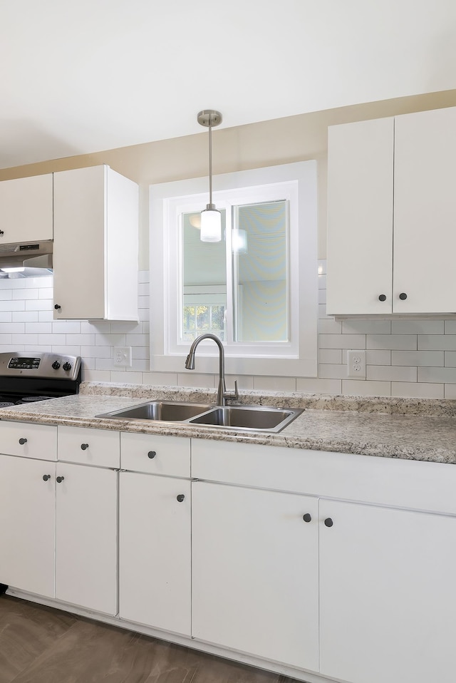 kitchen with decorative backsplash, sink, white cabinets, and hanging light fixtures