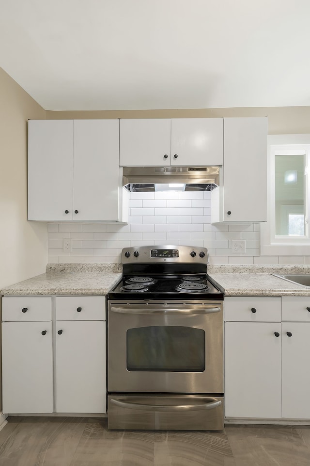 kitchen featuring decorative backsplash, white cabinets, and stainless steel electric range oven