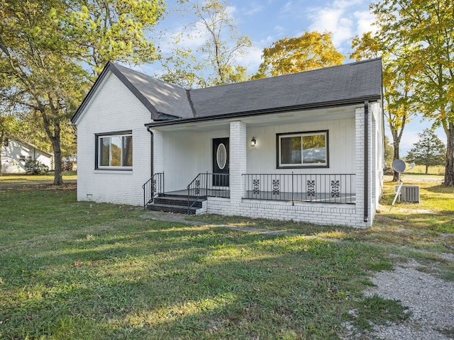 view of front of house with covered porch, a front yard, and central AC