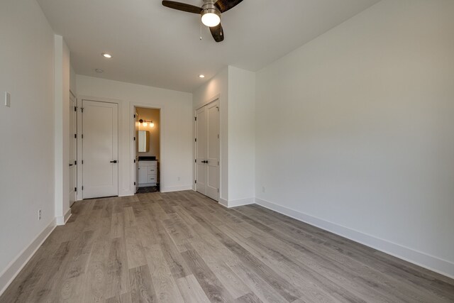 unfurnished bedroom featuring connected bathroom, light hardwood / wood-style flooring, and ceiling fan