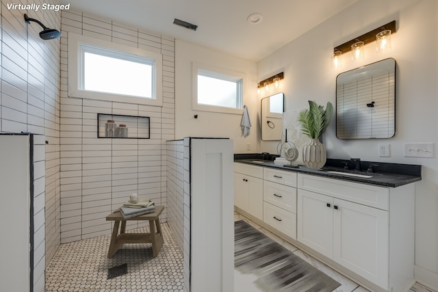 bathroom featuring vanity, a wealth of natural light, and tiled shower